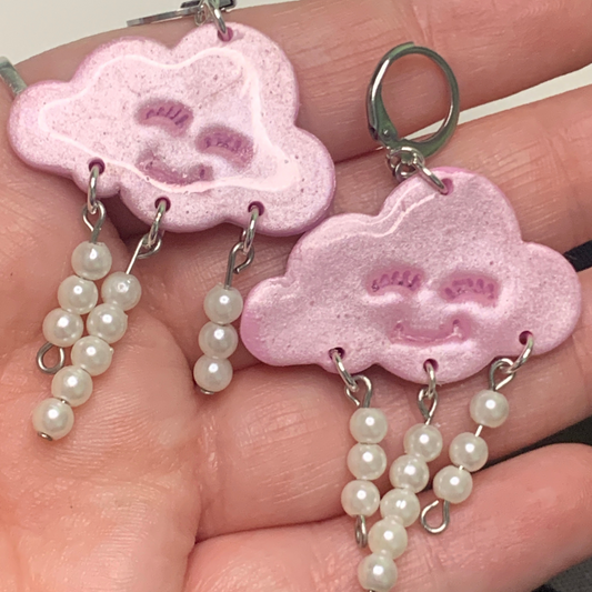 Pink Happy Cloud Dangles - Studio Mintii Channel your inner dreamer with these playful Pink Happy Cloud Dangles. These glittery pink cloud dangle earrings add a touch of whimsy to any outfit. Embrace your unique style with a touch of sparkle and charm. (Go ahead, wear them on a cloudy day!) Note: Last image is an example of different types of bead detailing I can do. Options go from left to right as; Beads 1, 2, or 3  #