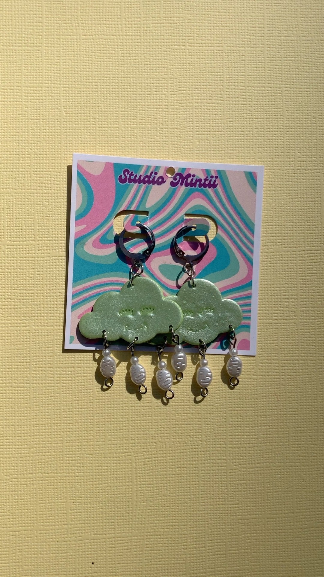 Green Happy Cloud Dangles - Studio Mintii Add some playful charm to your outfit with our Green Happy Cloud Dangles. These glittery green earrings are accented with faux pearls for a touch of elegance. Get ready to shine like a cloud on a sunny day! Note: Last image is an example of different types of bead detailing I can do. Options go from left to right as; Beads 1, 2, or 3  #