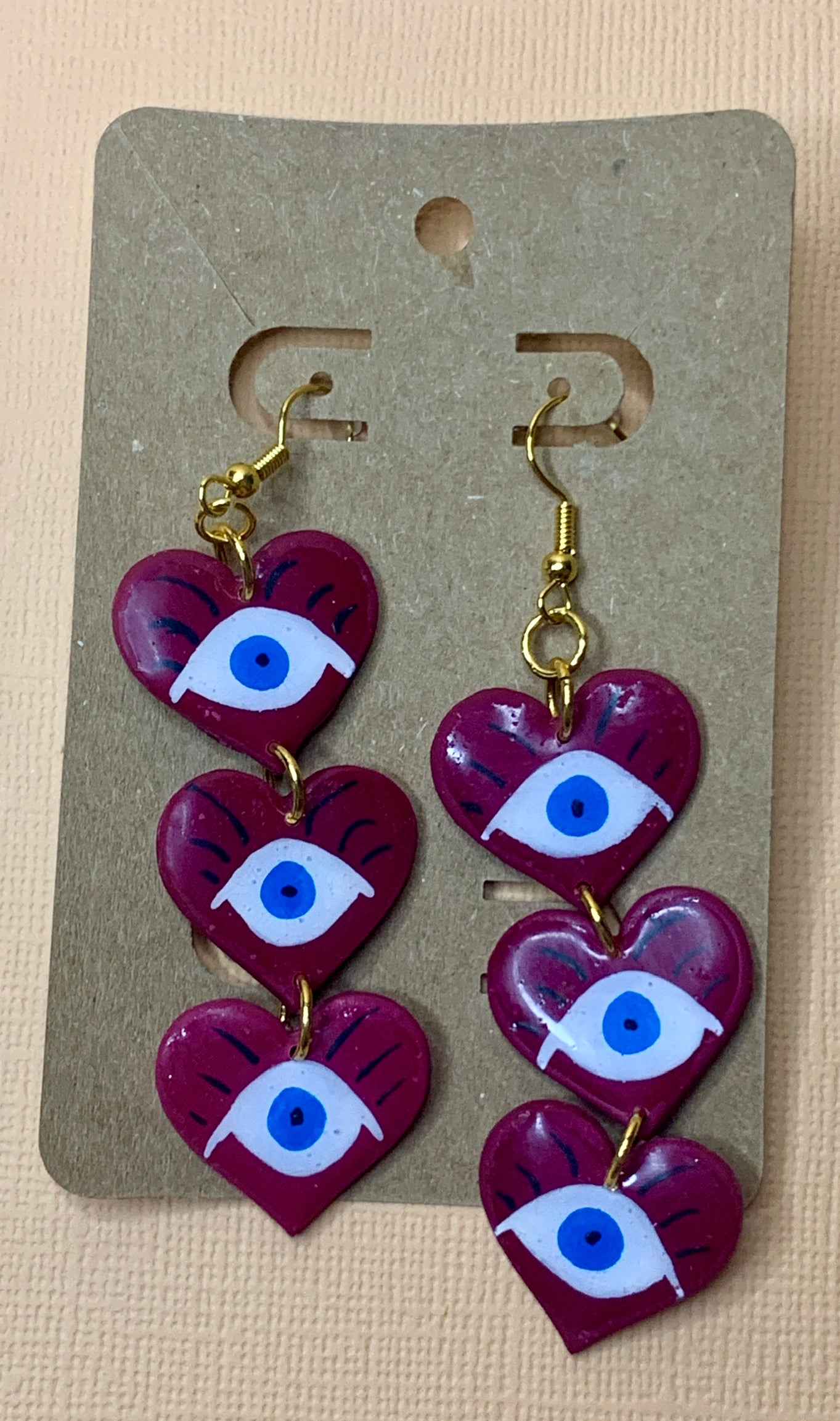 Evil Eye Drop Trio - Studio Mintii Keep bad vibes away with our Evil Eye Drop Trio! These quirky dangle earrings are handmade from polymer clay and resin, ensuring quality and durability. Make a statement and protect yourself at the same time - talk about killing two birds with one stone! Note: I played around to get this purple colour. For future stock, these will be made in a red colour scheme.  #