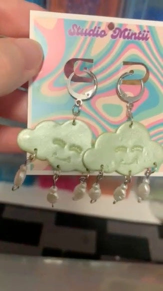 Green Happy Cloud Dangles - Studio Mintii Add some playful charm to your outfit with our Green Happy Cloud Dangles. These glittery green earrings are accented with faux pearls for a touch of elegance. Get ready to shine like a cloud on a sunny day! Note: Last image is an example of different types of bead detailing I can do. Options go from left to right as; Beads 1, 2, or 3  #